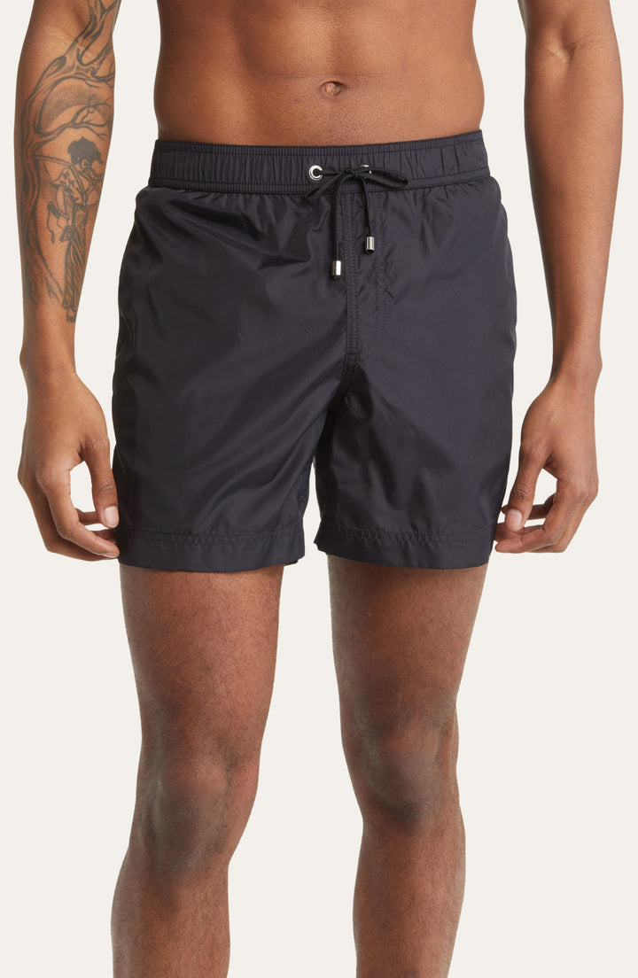 Model wearing black Easton Logo embroidered tailored swim shorts by Prince & Bond