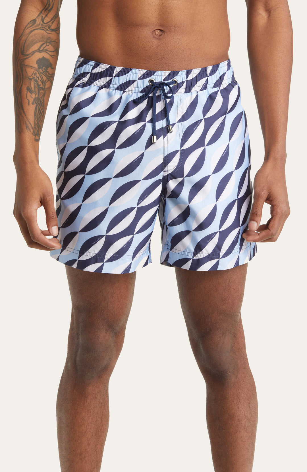Model wearing Easton Blue and White Geometric print swim shorts by Prince & Bond